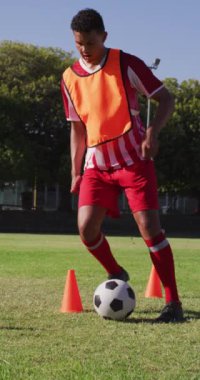 Saha tekmesindeki çift ırklı futbolcunun dikey videosu. Erkek futbol takımı, kapsayıcılık ve takım sporlarına uygunluk.