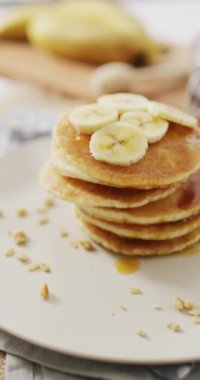 Üzerinde muz dilimleri olan Amerikan usulü PANCAKES 'in dikey videosu. Ev yemeği, tatlı ikram, yemek, lezzet ve besin.