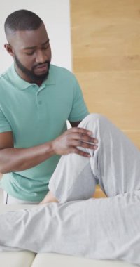 Afro-Amerikan erkek fizyoterapistin kıdemli bir hastayla egzersiz yaptığı dikey bir video. Yaşlılar sağlık ve huzurevi konsepti.
