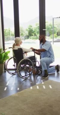 Afro-Amerikan erkek fizyoterapistin kıdemli bir hastayla egzersiz yaptığı dikey bir video. Yaşlılar sağlık ve huzurevi konsepti.