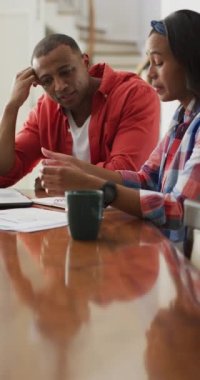 Afrika kökenli Amerikalı bir çiftin oturma odasında mali konuları tartışırken çekilmiş dikey videosu. ev yaşamında ve evde mali zorluklar.