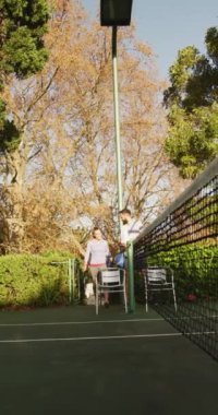 Kafkasyalı mutlu çiftin tenis oynamaya hazırlandığı dikey video. Spor, aktif yaşam tarzı ve tenis eğitimi kavramı.