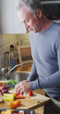 Beyaz adamın oturma odasında yemek pişirdiği dikey video. Evde yalnız vakit geçirmek..