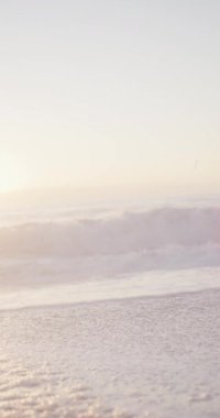 Dalgalı deniz ve güneşli sahilde mavi gökyüzünün dikey videosu. Plaj tatilinde boş zaman geçirmek.