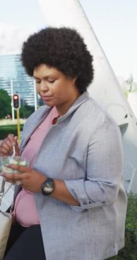 Melez bir kadının sokakta yemek yerken çekilmiş dikey videosu. Şehirde yaşıyor ve ayak işlerini yapıyor..