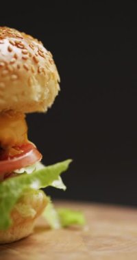 Gri arka planda salatalı taze ev yapımı hamburgerin dikey videosu. Taze ev yapımı fast food..