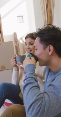 Yeni evde kahve içen mutlu Asyalı çiftin dikey videosu. Yaşam tarzı, taşınma ve yeni ev konsepti