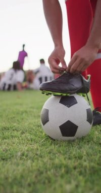 Saha tekmesindeki çift ırklı futbolcunun dikey videosu. Erkek futbol takımı, kapsayıcılık ve takım sporlarına uygunluk.