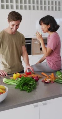 Birlikte yemek pişiren ve şarap içen mutlu çiftin dikey videosu. Aşk, ilişki ve birlikte kaliteli zaman geçirme kavramı.