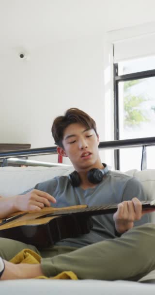 Κάθετο Βίντεο Ασιάτη Έφηβο Παίζει Κιθάρα Στο Σαλόνι Περνώντας Χρόνο — Αρχείο Βίντεο