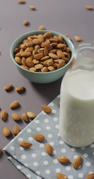 背景にアーモンドとミルクのボトルのボウルの垂直ビデオ 健康的なスナック食品 — ストック動画