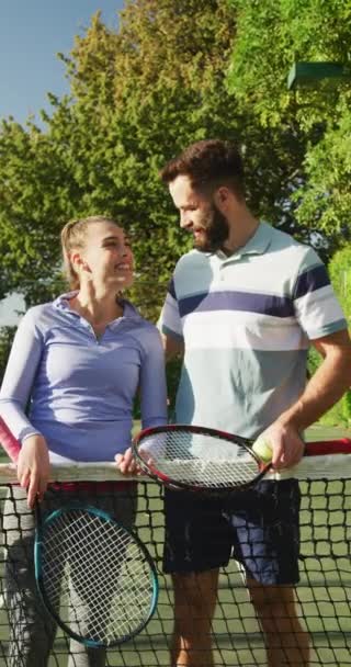 幸せな白人カップルの垂直ビデオテニスラケットを採用しています スポーツ アクティブライフスタイルとテニスのトレーニングコンセプト — ストック動画
