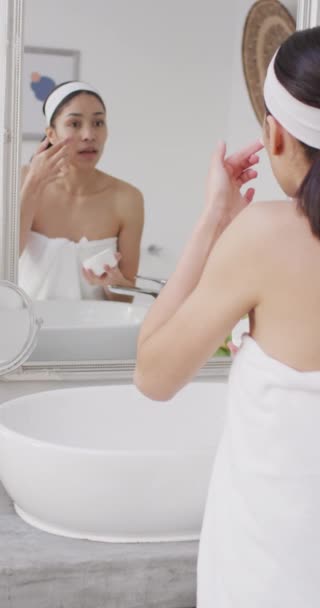 Vidéo Verticale Femme Biraciale Appliquant Crème Sur Visage Dans Salle — Video