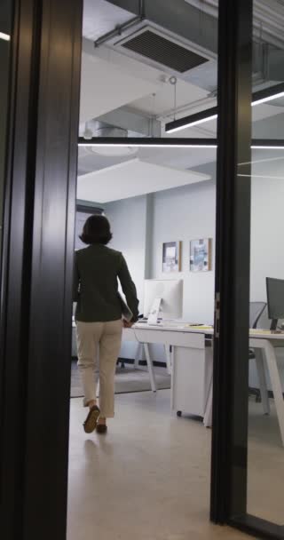 亚洲女商人在办公室拿着手提电脑走路的垂直录像 在现代化的办公室工作 — 图库视频影像