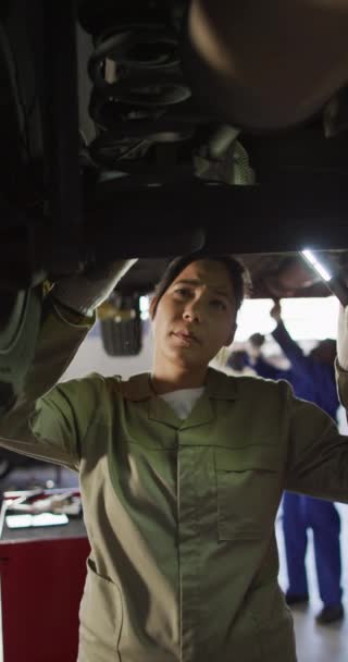 出生女性の車の整備士のチェック車の垂直ビデオ 車の修理店で働くと小さな女性的なビジネスコンセプトを実行している — ストック動画
