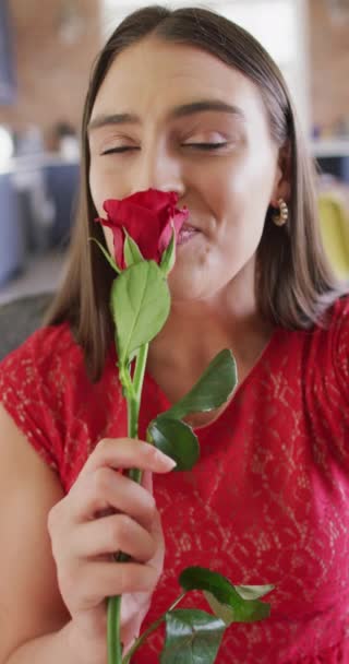 笑着拿着红玫瑰的高加索女人做情人节视频电话的垂直视频 利用通信技术庆祝浪漫 — 图库视频影像