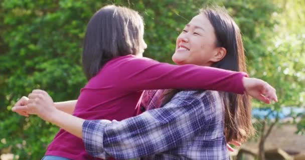 亚洲快乐的母亲和女儿在花园里拥抱和玩乐的视频 关系和花质量时间在一起的概念 — 图库视频影像
