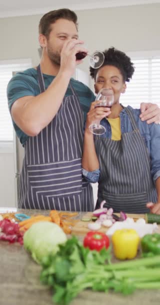 キッチンで食事を準備し ワインを飲む幸せな多様なカップルの垂直ビデオ 家で一緒に質の高い時間を過ごす — ストック動画