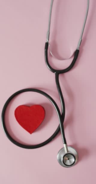 Вертикальне Відео Накладного Вигляду Червоного Серця Стетоскопа Рожевому Фоні Медичні — стокове відео