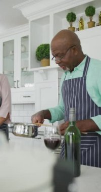 Mutfakta yemek pişiren yaşlı çiftin dikey videosu. Aile, evde ve bedende birlikte vakit geçirir..