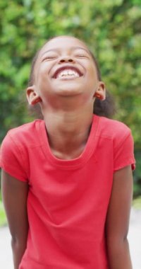 Bahçedeki mutlu Afrikalı Amerikalı kızın portresinin dikey videosu. evde zaman geçirmek.