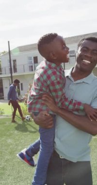 Mutlu Afro-Amerikan ailesinin futbol oynadığı dikey video. Ev kavramında aileyle kaliteli zaman geçirmek.