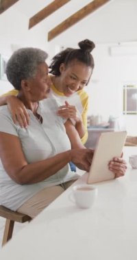 Yetişkin kızıyla tablet kullanan mutlu Afrikalı Amerikalı kadının dikey videosu. Üst düzey sağlık ve tıbbi fizyoterapi tedavisi.