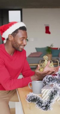 Noel Baba şapkası takan Afro-Amerikan bir adamın video görüntüsü. Video görüşmesi için laptop kullanıyor. Noel 'de evde yalnız vakit geçirmek..