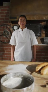 Pastanedeki mutlu Asyalı kadın fırıncının dikey portresi. küresel iş ve fırın.