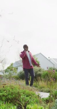 Bahçede yürüyen mutlu Afro-Amerikan erkeklerinin dikey videosu. Yaşlı yaşam tarzı, emeklilik tarzı, aktif boş zaman..