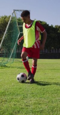 Saha tekmesindeki çift ırklı futbolcunun dikey videosu. Erkek futbol takımı, kapsayıcılık ve takım sporlarına uygunluk.