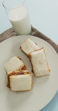 Tabakta sandviçler ve bir bardak sütün dikey videosu. yemek, aşçılık, yemek ve beslenme konsepti.