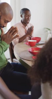 Afro-Amerikan mutlu karı-kocanın kahvaltı masasında şükran duası edişinin dikey video portresi. Aile, aile hayatı ve birliktelik kavramı dijital olarak oluşturulmuş video.