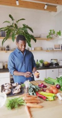 Mutfakta durup yemek pişiren mutlu Afro-Amerikan adamın dikey videosu. Evde yalnız zaman geçirmek..