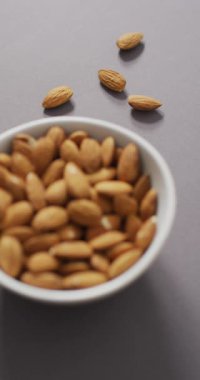 Leylak arka planında bir kase bademin dikey videosu. sağlıklı abur cubur, diyet ve beslenme.