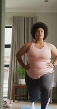 Evde egzersiz yapan melez bir kadının dikey videosu. ev ve beden dahil olmak üzere aktif zaman harcamak.