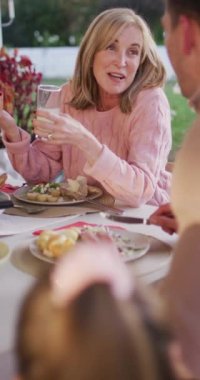 Yetişkin bir çocukla aile yemeği masasında konuşan Kafkas bir annenin dikey videosu. Aile, aile hayatı ve birliktelik kavramı dijital olarak oluşturulmuş video.