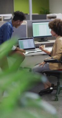 Dizüstü bilgisayarlı mutlu kadın iş arkadaşlarının dikey videosu. İş adamları ve ofis kavramında çalışmak.