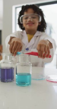 Evde tek başına deneyler yapan mutlu melez çocuğun dikey videosu. evde zaman geçirmek.