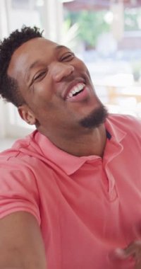 Mutlu Afro-Amerikan bir adamın görüntülü konuşma yaptığı dikey video. Evde yalnız zaman geçirmek..