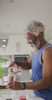 Yaşlı Afro-Amerikan adamın evde kahvaltı hazırlarken çekilmiş dikey videosu. evde sağlıklı, aktif emeklilik.