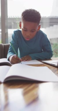 Ödev yapan Afrikalı Amerikalı çocuğun dikey videosu. Çocukluk, eğitim ve ev kavramında zaman geçirme.