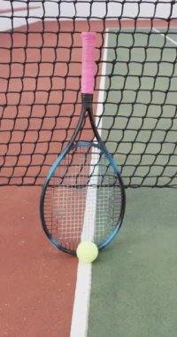 Tenis kortunda sarı tenis topu ve raketin dikey videosu. sağlıklı ve aktif emeklilik.