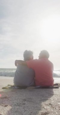 Sunny Beach 'te kucaklaşan mutlu çift çiftinin dikey videosu. sağlıklı, aktif emeklilik plaj tatili.