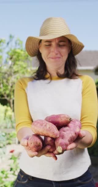 日当たりの良い庭での笑顔の白人女性の垂直ビデオは 新鮮な収穫ビートを運ぶ 健康的な食事と十分なライフスタイル身体的包容力 — ストック動画