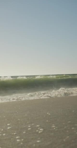 日当たりの良いビーチで波と青空と海の垂直ビデオ ビーチホリデーで自由時間を過ごすと — ストック動画