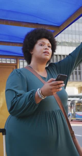 用智能手机在街上走来走去的一个超大号的女人的垂直视频 在城市里生活和跑腿 — 图库视频影像