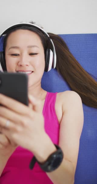 Vertikální Video Usměvavou Asijskou Ženou Která Odpočívá Sluchátkách Používá Smartphone — Stock video