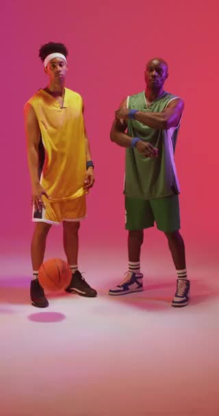 Вертикальне Відео Двох Різноманітних Чоловічих Баскетболістів Ячем Рожевому Фоні Концепція — стокове відео