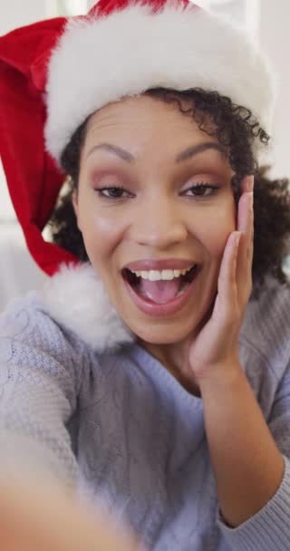 サンタ帽子を被った幸せなアフリカ系アメリカ人女性の縦ビデオ通話を持っています 家庭だけで質の高い時間を過ごす — ストック動画